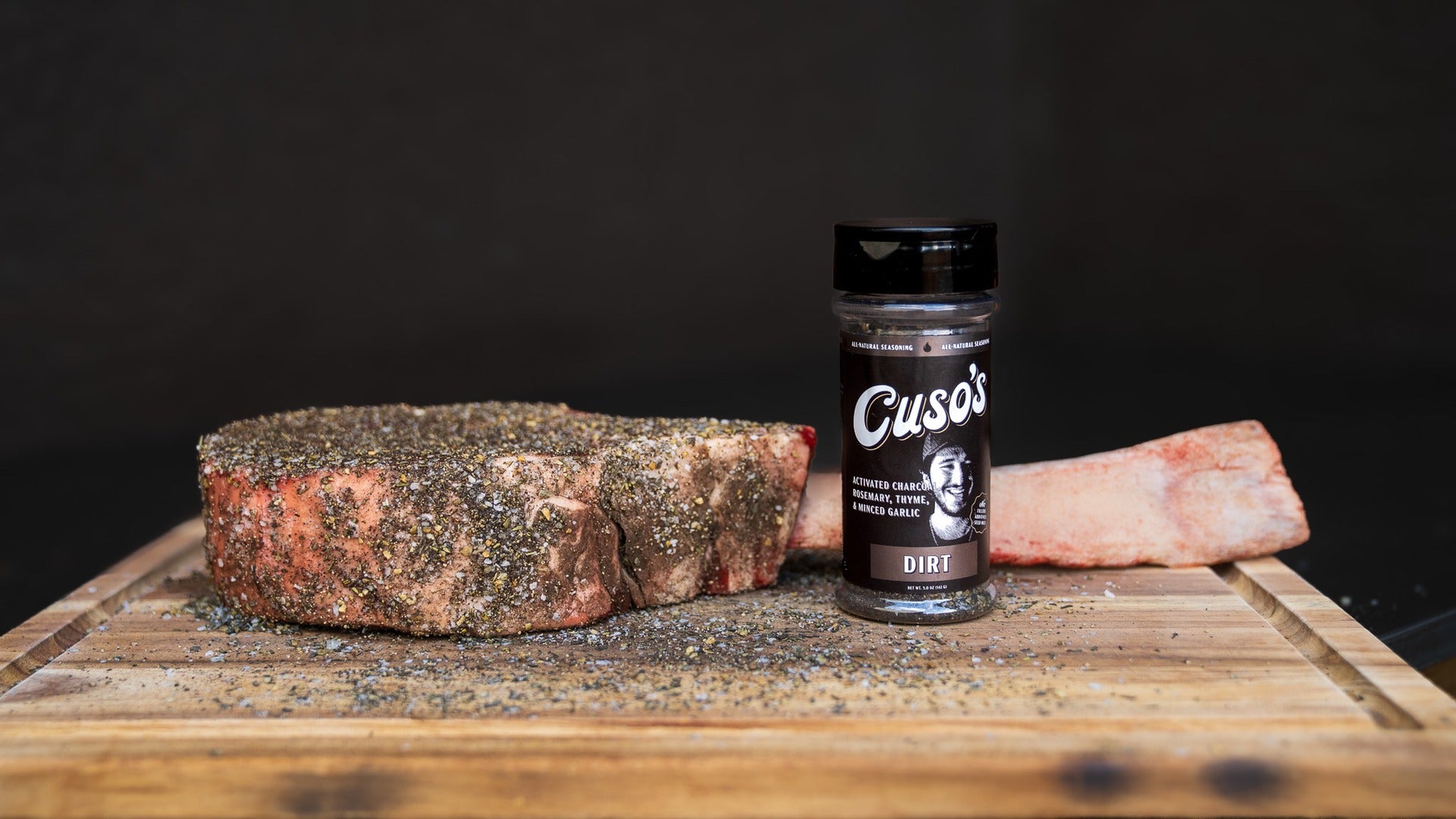 Cuso's Dirt seasoning bottle with a piece of meat on a wooden surface